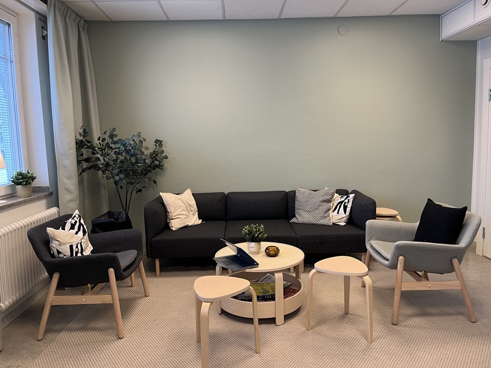 Loungehörna med soffa, fåtöljer och små bord i en ljus, ombonad miljö.